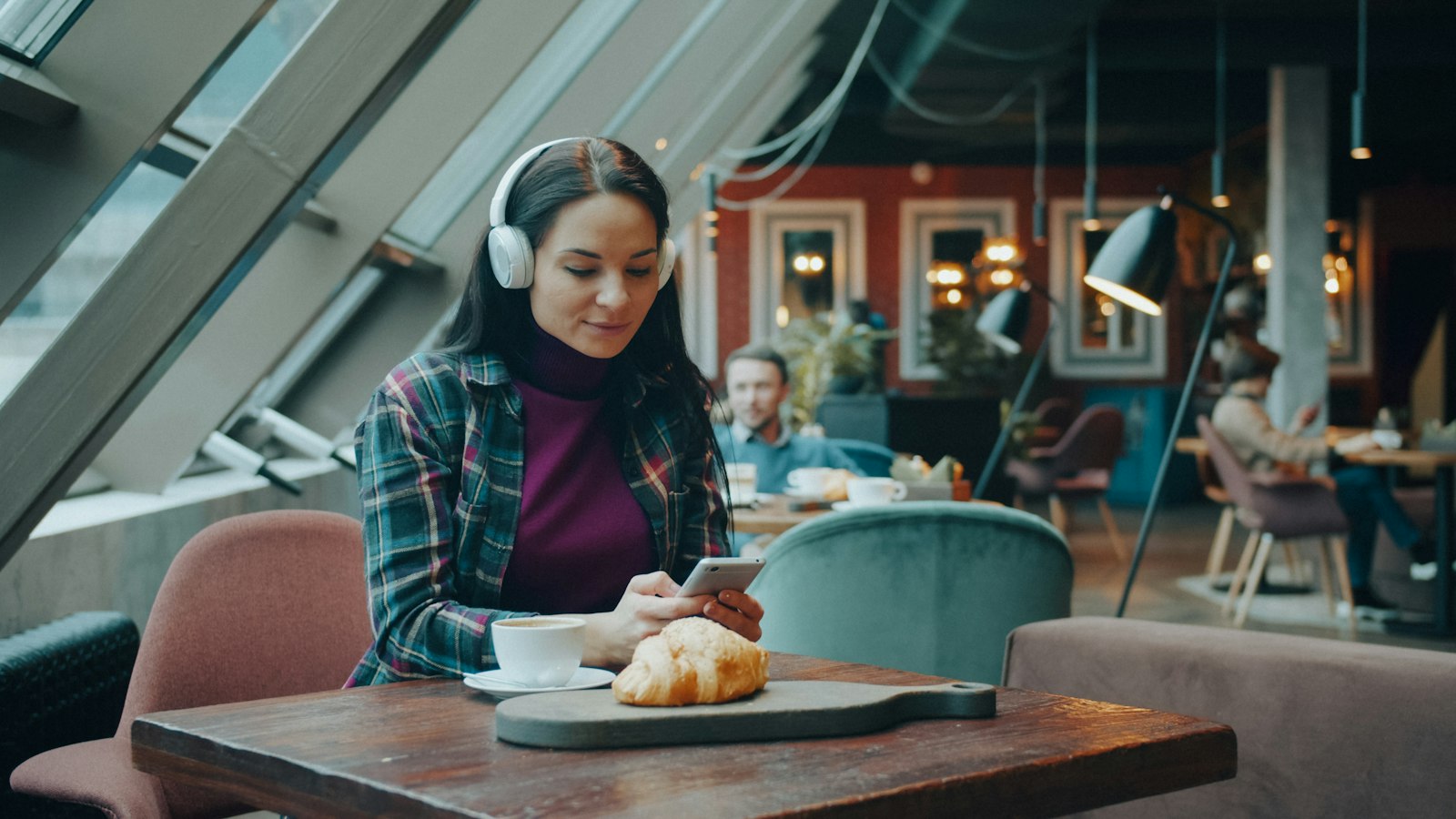 Kundin nutzt ihr Telefon an einem Cafétisch